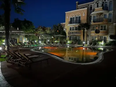 a swimming pool in front of a building at night at MARINA Apartments in Ravda