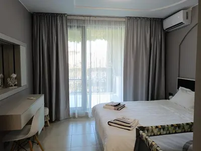a hotel room with a bed and a desk and a window at Green Line Apartament Sozopol in Sozopol