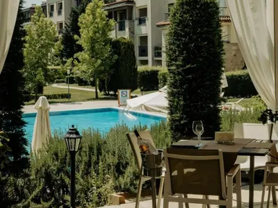 a table and chairs next to a swimming pool at Green Line Apartament Sozopol in Sozopol