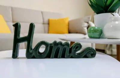a green sign that says home on a table at Ika apartment in Burgas City