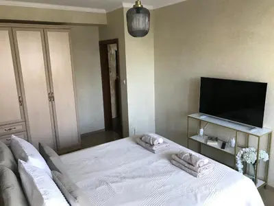 a bedroom with a white bed and a flat screen tv at Ika apartment in Burgas City
