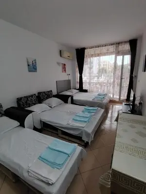 a room with four beds in a room with a couch at Сънсет Бийч 3 in Sunny Beach