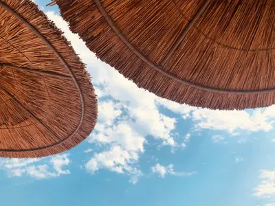two large straw umbrellas against a blue sky at Bułgaria na lato apartament z widokiem na morze Sozopol in Sozopol