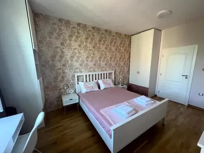 a bedroom with a white bed with a pink bedspread at Sea Vibes - Modern Apartment Near the Beach & City Center, Burgas in Burgas City