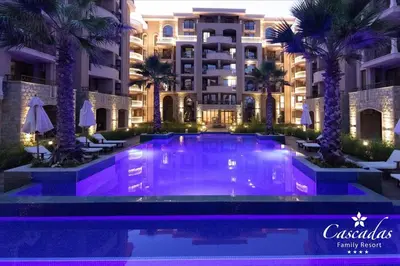 a swimming pool in front of a building with palm trees at Cascadas Family Resort in Sunny Beach