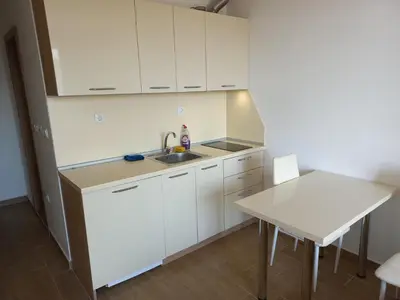 a kitchen with white cabinets and a sink and a table at Cascadas Family Resort in Sunny Beach