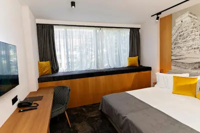 a bedroom with a bed and a desk and a window at MM Boutique Hotel in Burgas City