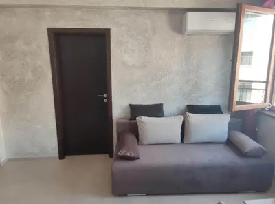 a couch with pillows sitting in front of a door at Apartament Piero in Pomorie