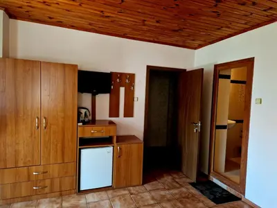 a kitchen with wooden cabinets and a white dishwasher at Цар Калоян in Primorsko