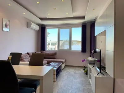 a living room with a couch and a table at Апартамент Чаролит / Apartment Charoite in Burgas City