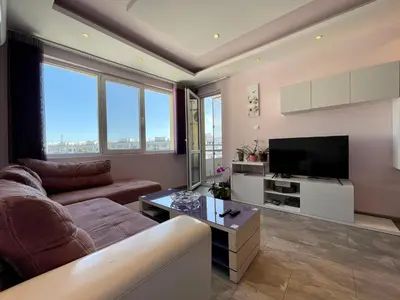 a living room with a couch and a flat screen tv at Апартамент Чаролит / Apartment Charoite in Burgas City
