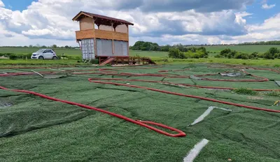 a field with green grass with red extension hose at Gala park fpv in Avren