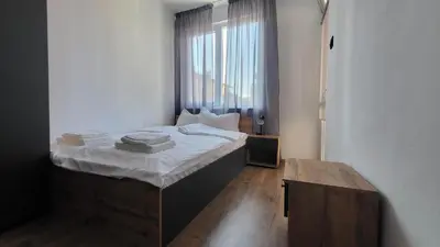 a bedroom with a bed with white sheets and a window at Q Аpartment in Tsarevo
