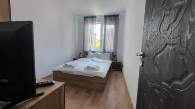 a bedroom with a bed and a door with a television at Q Аpartment in Tsarevo