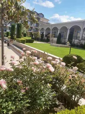 a garden with pink roses in front of a building at Studio E32 Atia Resort Chernomoretz in Chernomorets
