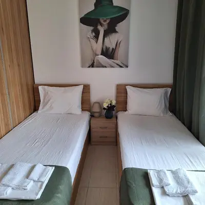 two beds in a room with a picture of a woman at Апартамент Blue в местност Каваци, Созопол in Sozopol