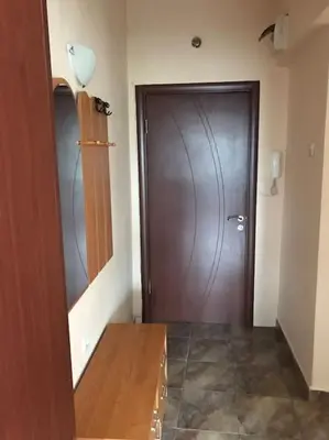 a hallway with a wooden door and a wooden table at Star Ray Apartment in Varna City