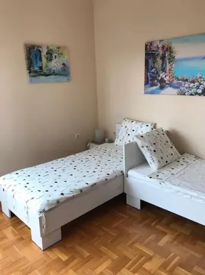 two white beds in a room with wooden floors at Star Ray Apartment in Varna City
