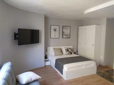 a bedroom with a bed and a flat screen tv at Студио Ирма in Burgas City