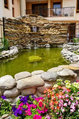 a pond with a fountain in a garden with flowers at TSB Roxy Apartments in Sunny Beach
