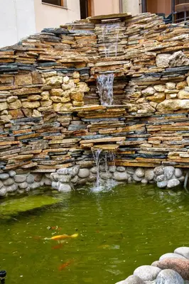 a stone wall with a water fountain in a pond at TSB Roxy Apartments in Sunny Beach