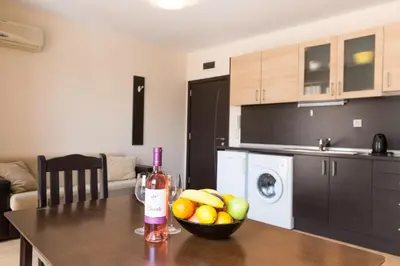 a kitchen with a table with a bowl of fruit and a bottle of wine at TSB Roxy Apartments in Sunny Beach
