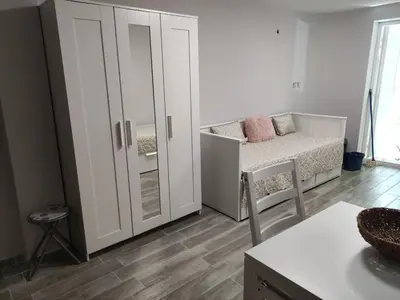 a living room with a bed and a cupboard at Студио за нощувки в центъра на град Бургас. in Burgas City