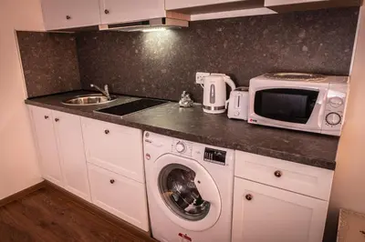 a kitchen with a washing machine and a microwave at bellissimo студио близо до плажа in Ravda