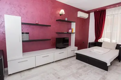 a bedroom with a bed and a tv and red wall at Polina Beach in Sozopol
