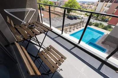 a balcony with two wooden benches and a swimming pool at Polina Beach in Sozopol