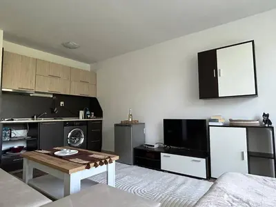 a living room with a table and a kitchen at Лятно студио in Sveti Vlas