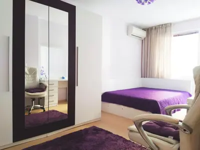 a bedroom with a mirror and a bed and a chair at Modern apartment in Burgas in Burgas City