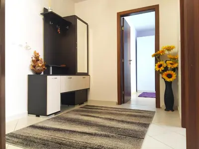 a hallway with a mirror and a vase of flowers at Modern apartment in Burgas in Burgas City