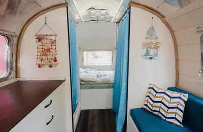 a small room with a bed in a trailer at Luxury Vintage Airstream RV/Caravan Retro Charm Meets Comfort in Kiten