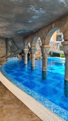 a swimming pool with blue water and pillars at Sweet Home 2 Apartment in Sunny Beach
