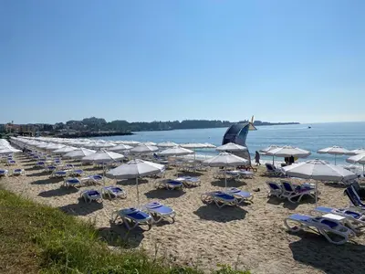 a bunch of chairs and umbrellas on a beach at Luxury First Line apartment with pool and sea view in complex Oazis in Ravda