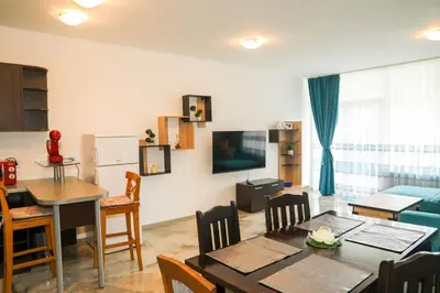 a living room with a table and a dining room at Luxury First Line apartment with pool and sea view in complex Oazis in Ravda