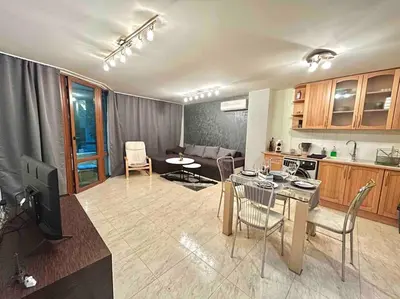a kitchen and a living room with a table and chairs at By The Sea Apartment in Varna City