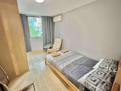 a bedroom with a bed and a chair in it at By The Sea Apartment in Varna City