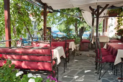 an outdoor restaurant with tables and chairs and an umbrella at Vromos Guest House in Chernomorets