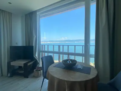 a living room with a table and a large window at PARADISO 'В' 207 Two Bedroom Apartment in Nesebar