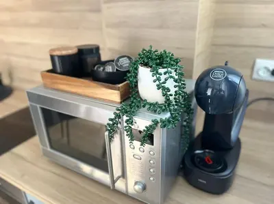a table with a toaster and a microwave with plants on it at Sea Garden Apartment in Burgas City