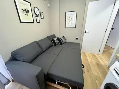 a living room with a black couch in a room at Sea Garden Apartment in Burgas City