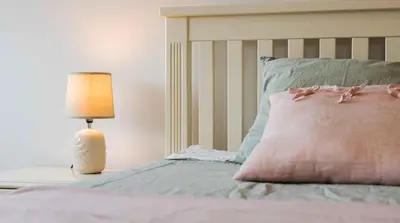 a bed with a pink pillow and a lamp at Central DELUXE Apartment in Burgas City