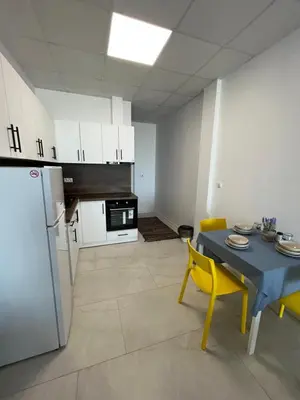a kitchen with a table and yellow chairs and a refrigerator at Aliara Dilara Beach Apartments in Pomorie