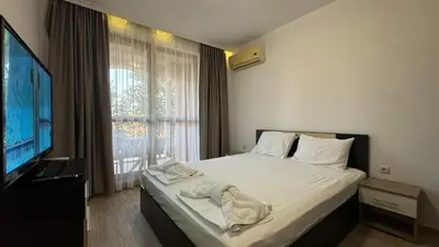 a bedroom with a bed and a tv and a window at Bratanov Cascadas Ravda in Ravda