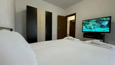 a bedroom with a large white bed and a flat screen tv at Bratanov Cascadas Ravda in Ravda