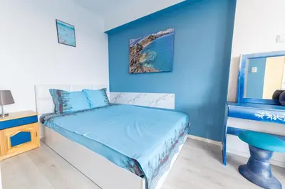 a bedroom with a bed and a blue wall at Casa Del Mare in Chernomorets