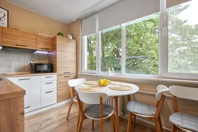 a kitchen with a white table and chairs and windows at LAZUR first line in Burgas City