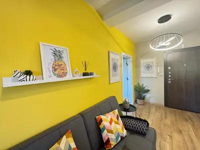 a living room with a couch and a yellow wall at LAZUR first line in Burgas City
